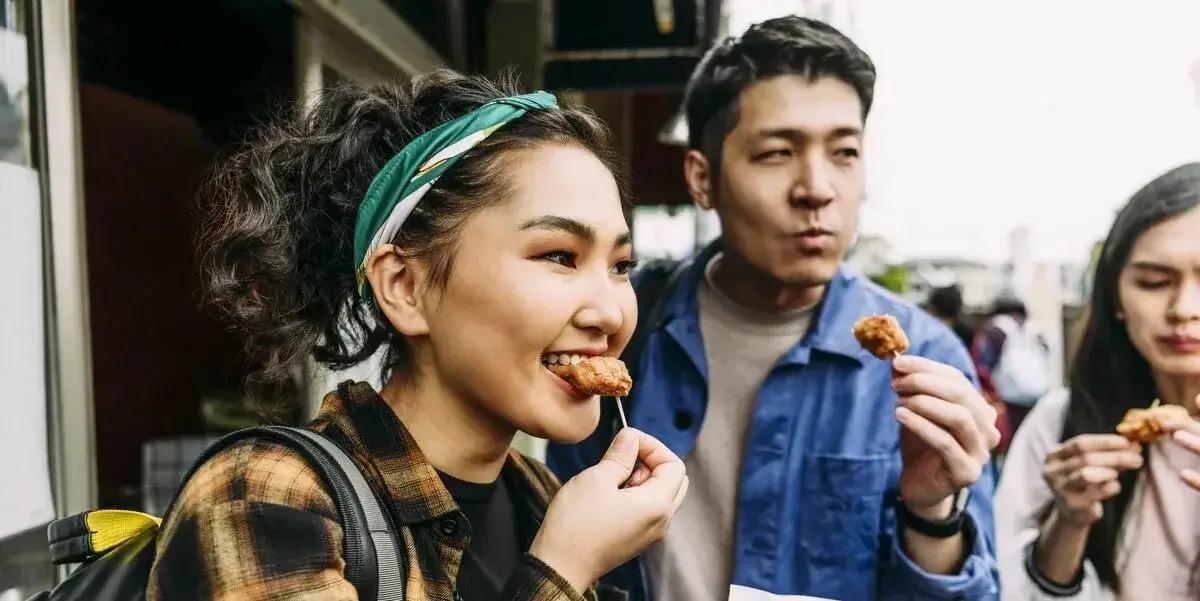 A person enjoying local street food in an Asian market.