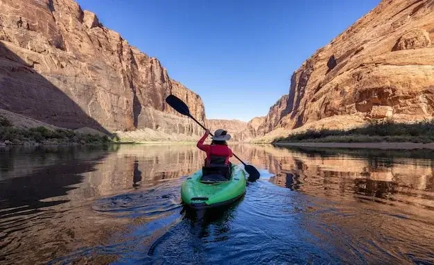 A kayaker paddling through a dramatic canyon.