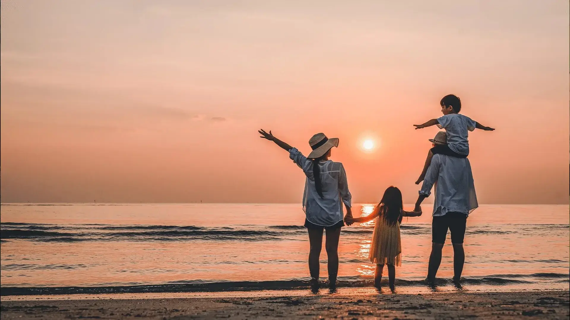 A happy family laughing on a beach at sunset.