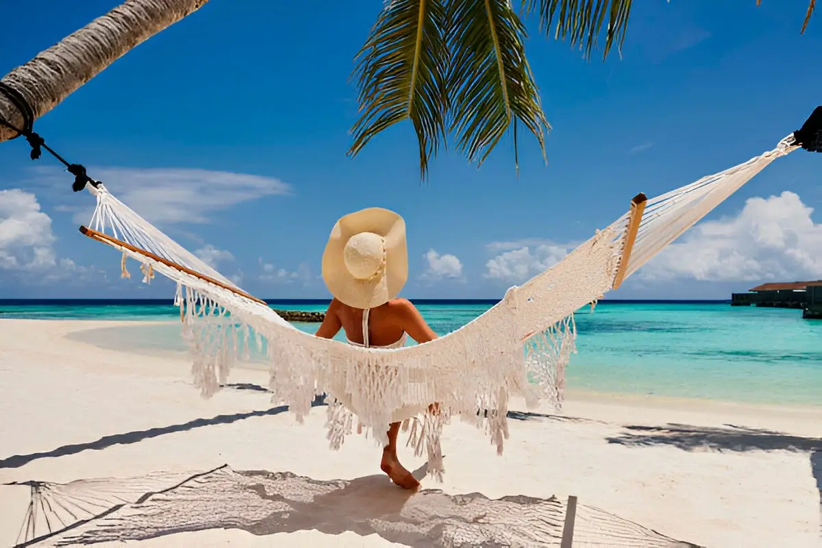 The same person relaxing in a hammock on a tropical beach, representing the 'after' state.
