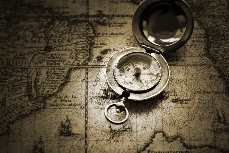 A well-worn travel journal and a vintage compass resting on an old map.